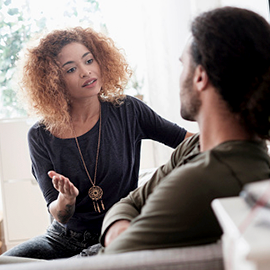 Young woman talking to man sitting on a sofa