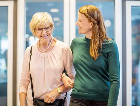 young woman walking arm and arm with senior woman