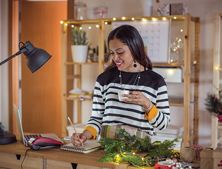 young woman holding coffee smiling while writing