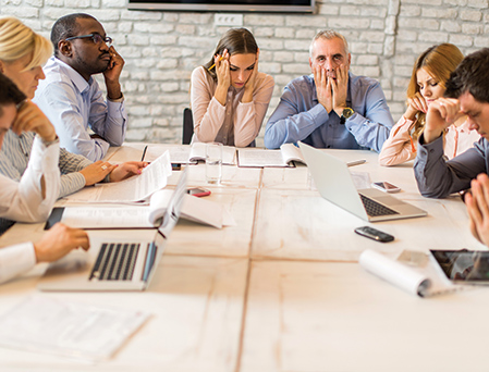 Group of co-workers at a meeting looking stressed and unhappy