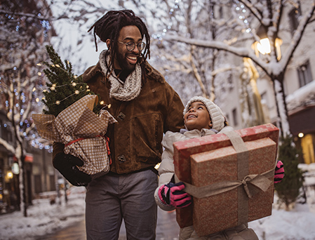 African-american father and young daughter carrying gift packages home