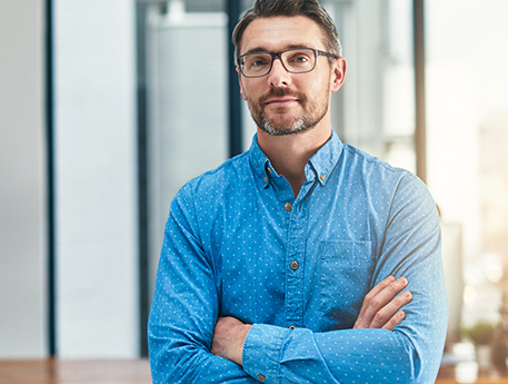 man in his early 40's with beard, glasses and arms crossed