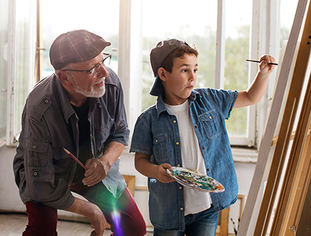 senior man teaching young grandson to paint