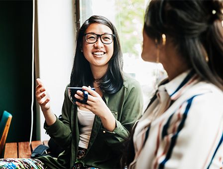 Asian 20s girl sitting with a girlfriend by a picture window